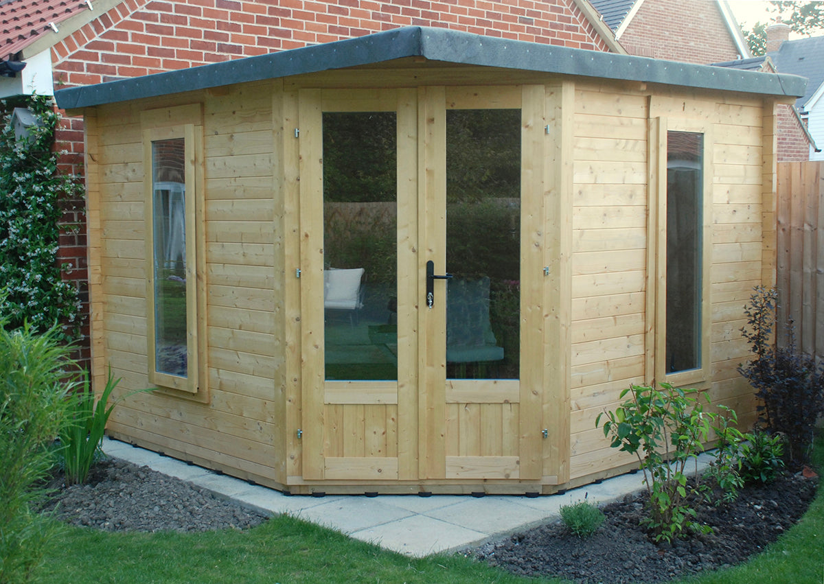A corner summerhouse with a plastic shed base kit installed on the timber bearers. The SHED BOOT elevates the timber floor off the wet concrete.